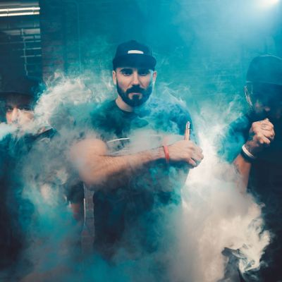 Three men vaping in an authentic room with brick walls